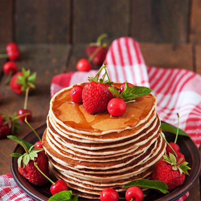 Pancakes with berries and syrup in a rustic style